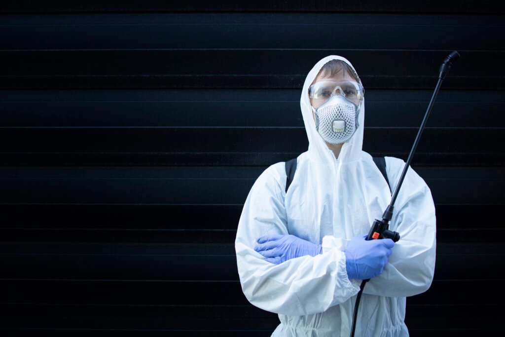 Pest control professional in protective gear holding a sprayer in Banora Point.